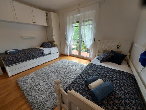 a bedroom with two beds and a large window at Apartman Doboga in Ozalj