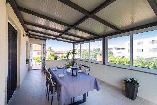 ein Esszimmer mit einem Tisch und einigen Fenstern in der Unterkunft Apartment Višnja in Zadar