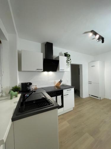 uma cozinha com armários brancos e um balcão preto em GROSS - REAL ESTATE em Leoben