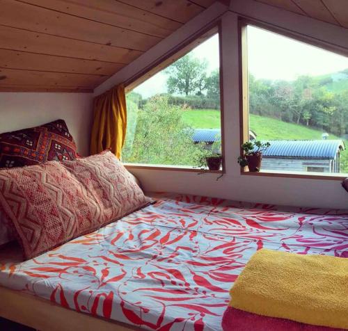 a bed sitting in a room with a window at Tree house and shepherds hut in Ashburton