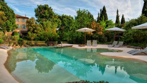 a swimming pool with umbrellas in a yard at La Bastide des Grands Chênes in Lambesc