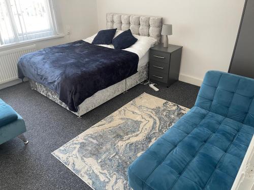 a bedroom with a bed and a blue couch at Spacious 3 bed flat near Watford Junction in Watford