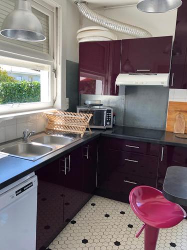 une cuisine avec des placards violets, un évier et un tabouret rouge dans l'établissement vacances-esprit-cabanes, à Andernos-les-Bains