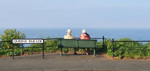 two people sitting on a bench looking at the ocean at St Michael's Guest House in Scarborough