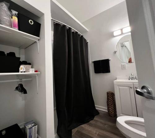 a bathroom with a black shower curtain and a sink at The Double Door Inn - Unit 1 in Matthews