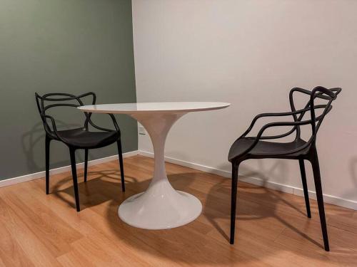 a white table and two black chairs in a room at Chacarita Sunset l Andes Park in Buenos Aires