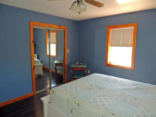 a blue bedroom with a bed and a window at Angel Rock Waterfront Cottages in Cape Vincent