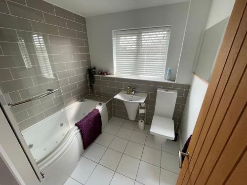 a bathroom with a tub and a sink and a toilet at Lovely modern, well-kept house in Sidcup