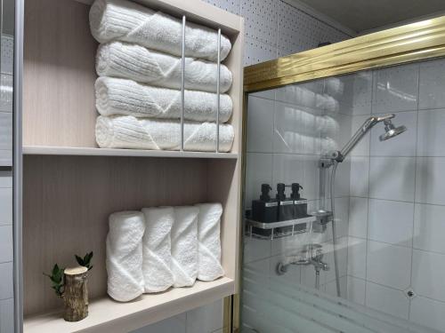 a bathroom with towels on a shelf and a shower at Posh_HongDae in Seoul