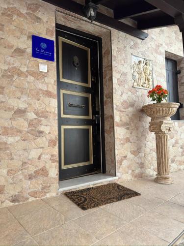 a black door on a stone wall with a vase at The Odyssey Holiday Home - Agios Ioannis, Pelion in Agios Ioannis Pelio