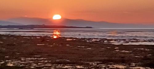 a sunset over a body of water with the sun setting at Twin room in Hoylake - 500 metres from Royal Liverpool Golf Course in Hoylake