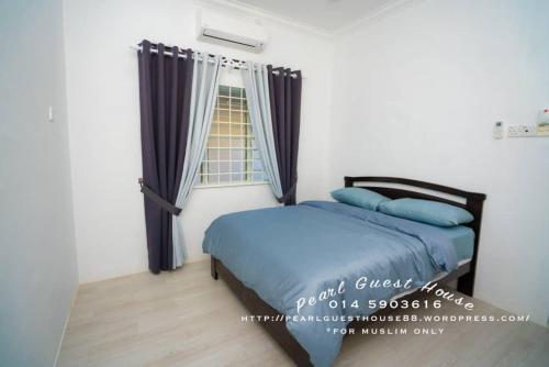een slaapkamer met een bed met blauwe kussens en een raam bij Pearl Guest House in Kerteh