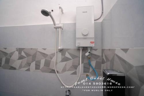 een douche in een badkamer met een witte muur bij Pearl Guest House in Kerteh