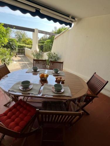 une table en bois avec des chaises et une tableastery ... dans l'établissement Spacieux appartement, grande terrasse, accès plage, à La Grande Motte