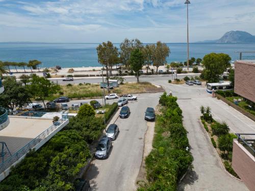 a street with cars parked in a parking lot next to the ocean at Delfini Hotel in Patra