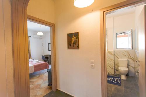 a bathroom with a toilet and a room with a bed at Kampos Kassiopi Apartment in Kassiopi