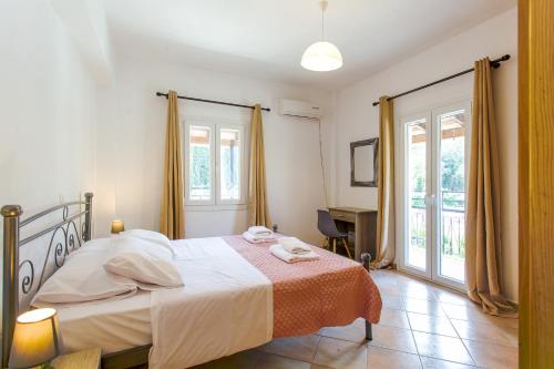 um quarto com uma cama, uma secretária e janelas em Kampos Kassiopi Apartment em Kassiopi