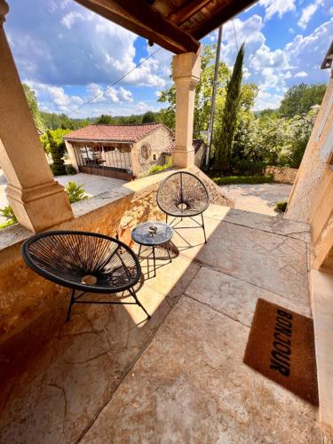 a patio with two tables and a building at Le Clos Des Buis Gîte de Charme AZUL in Cazals