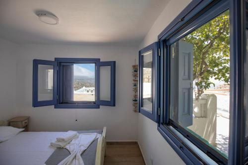 a bedroom with blue windows and a bed with towels on it at Thea Menetes in Karpathos Town