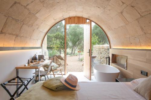 a bedroom with a bed and a table and a tub at Fincahotel Treurer - Olive Grove & Grand House - Adults Only in Algaida