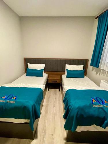 two beds in a room with blue sheets at Uzungöl Bungalow in Uzungol