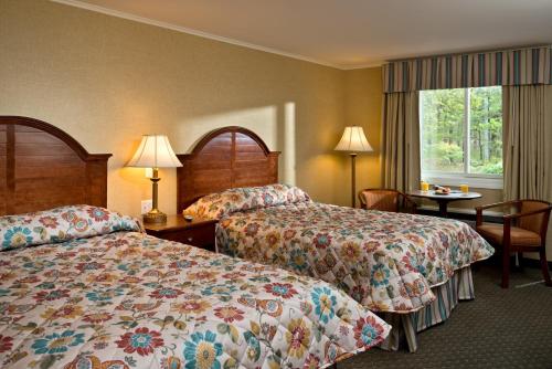 a hotel room with two beds and a table at Wellfleet Motel & Lodge in Wellfleet