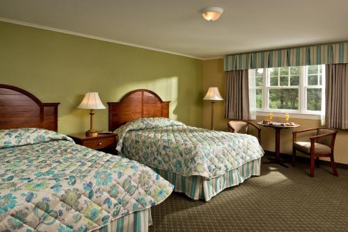 Cette chambre comprend 2 lits et une table. dans l'établissement Wellfleet Motel & Lodge, à Wellfleet