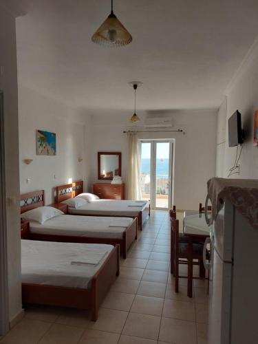a group of beds in a room with a window at Sunset Apartments in Kanali