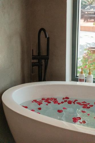 a bath tub filled with red flowers in a bathroom at Tuong Boutique Mui Ne in Mui Ne