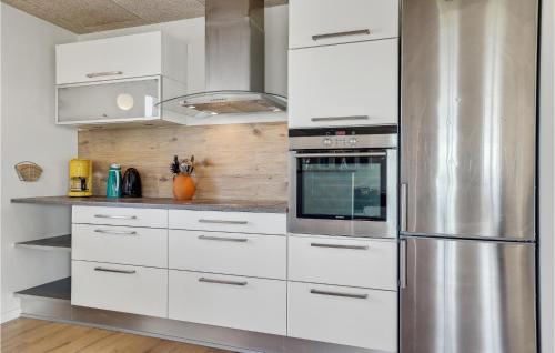 a kitchen with white cabinets and a stainless steel refrigerator at 3 Bedroom Beautiful Home In Tim in Tim