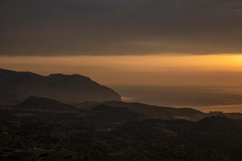 a view of the mountains with the sunset in the background at Thea Menetes in Karpathos Town