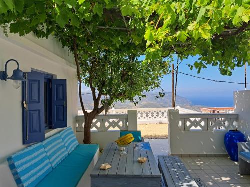 a blue couch sitting on a patio with a tree at Thea Menetes in Karpathos Town