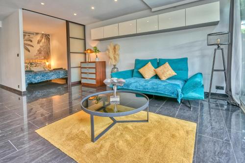 een woonkamer met een blauwe bank en een glazen tafel bij The Beach Dream in Saint-Laurent-du-Var