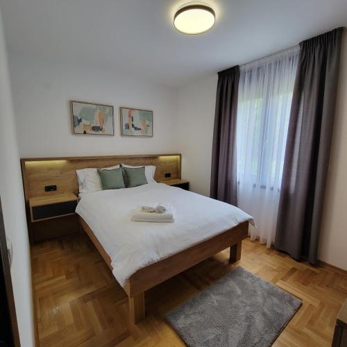 ein Schlafzimmer mit einem großen weißen Bett mit einem Fenster in der Unterkunft PIK Apartmani in Vrnjačka Banja
