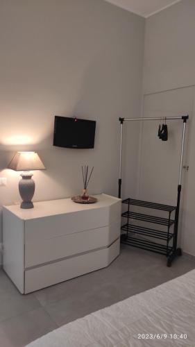 普利亞區格拉維納的住宿－Grazia Guest House，白色的客房设有一张桌子、一盏灯和一台电视机