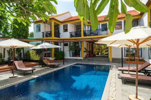 une piscine en face d'une maison avec des parasols dans l'établissement Tuong Boutique Resort Mui ne, à Mui Ne