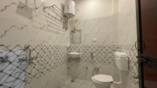a white tiled bathroom with a toilet and a sink at The Comfort Home Stay Ranthambhore in Sawāi Mādhopur