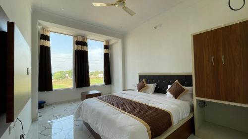 - une chambre avec un grand lit et 2 fenêtres dans l'établissement The Comfort Home Stay Ranthambhore, à Sawai Madhopur