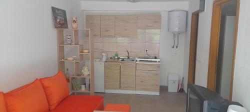 sala de estar con sofá naranja y cocina en Apartman NeSa Boracko jezero, en Konjic
