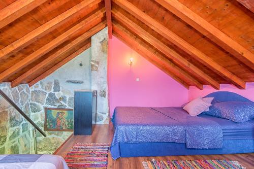 ein Schlafzimmer mit einem lila Bett im Dachgeschoss in der Unterkunft STONE HOUSE ANA in Škrip