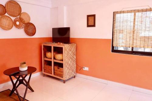 a room with orange walls and a shelf with baskets at Tiny yet Beautiful apartment in the heart of Phnom Penh, Near central market in Phnom Penh