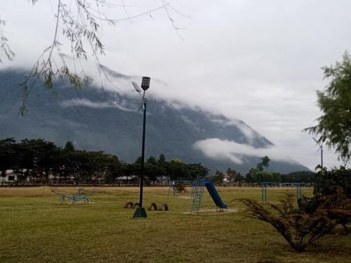 un parque con un parque infantil con una montaña al fondo en Suzet House, en Oxapampa