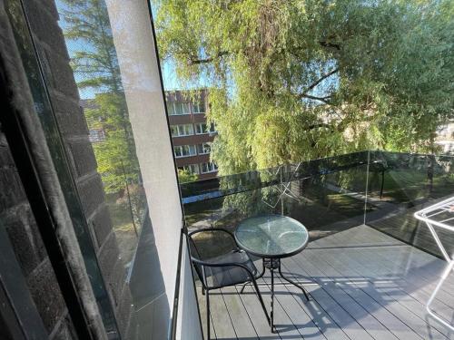 d'une table en verre et d'une chaise sur un balcon. dans l'établissement Birstonas Holidays Apartment, à Birštonas
