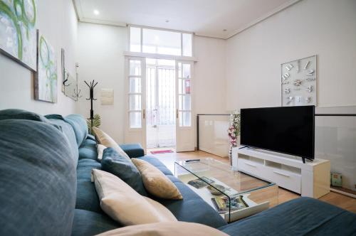 Apartamento Palacio Real de Madrid, histórico في مدريد: غرفة معيشة مع أريكة زرقاء وتلفزيون بشاشة مسطحة