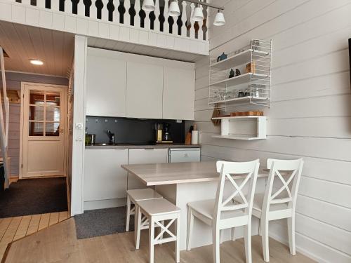 - une cuisine avec des placards blancs, une table et des chaises dans l'établissement Ylläs Nilimaja, à Ylläsjärvi