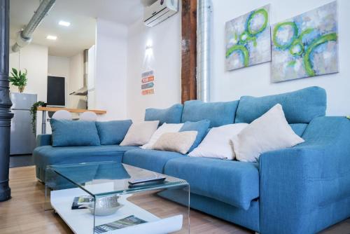 um sofá azul numa sala de estar com uma mesa de vidro em Apartamento Palacio Real de Madrid, histórico em Madri