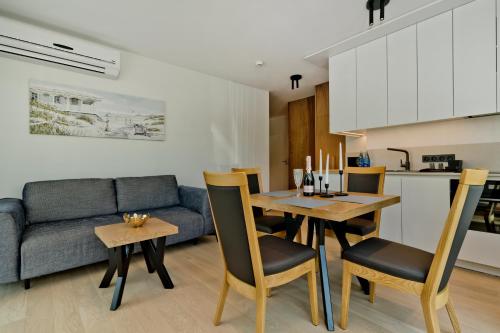 a kitchen and living room with a table and a couch at Apartamenty Wydma & Las BlueApart in Jastarnia