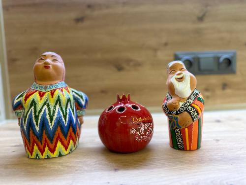 three ceramic figurines sitting on a table with an apple at Tashkent City Boulevard in Tashkent