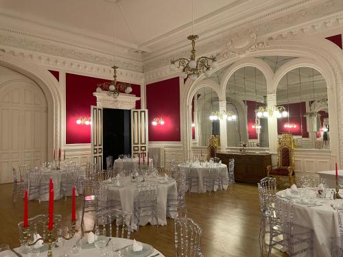 Habitación con mesas y sillas blancas y lámpara de araña. en Salon Boyer en Épernay