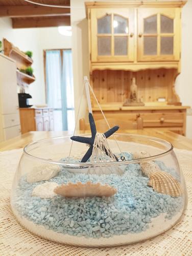 a glass bowl with a starfish and rocks on a table at House Gennemari in Torre delle Stelle